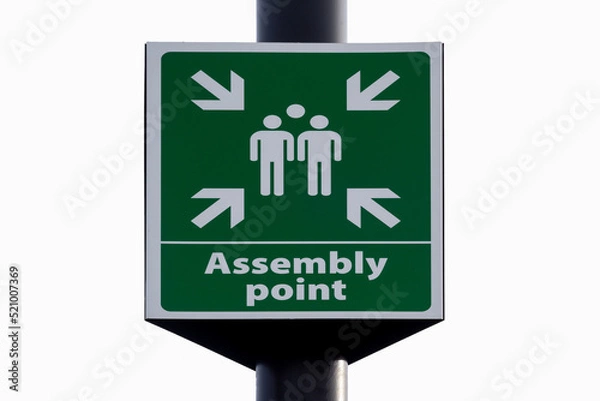 Fototapeta Emergency evacuation assembly point sign close up isolated against white background. 