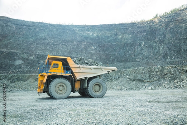 Fototapeta Quarry for iron ore extraction. Transportation of copper ore rocks by dump trucks. Large quarry yellow truck. Mining truck drives through the quarry, equipment for working with copper ore rocks. 