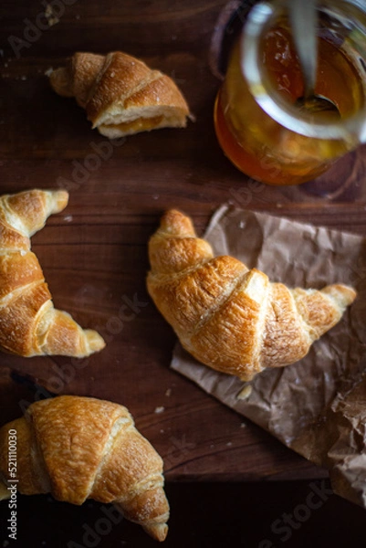 Fototapeta Small fresh croissants and a jar of fruit jen on a wooden table. Traditional Argentine medialoons. flat lay composition.