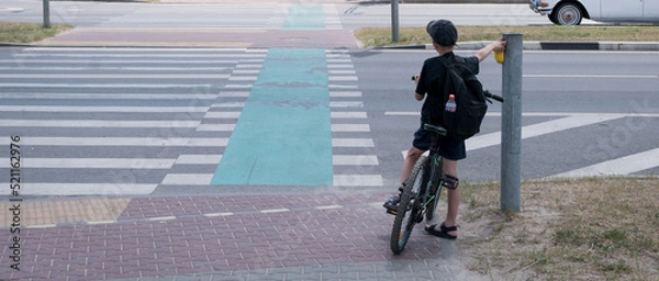 Fototapeta A little boy rides around the city on a bicycle