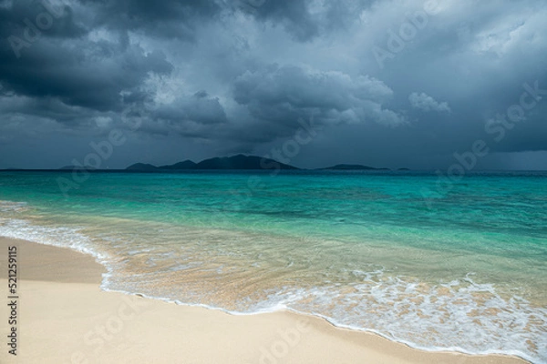 Fototapeta Jost Van Dyke surrounded by tropical squall clouds viewed across turquoise Caribbean waters from Apple Bay Beach on Tortola, BVI 