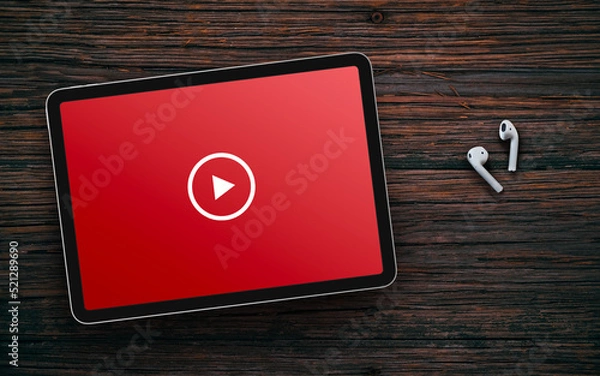 Obraz Play button on red screen of tablet and wireless earphones on dark wooden surface