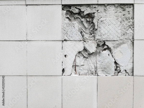 Fototapeta A wall with a broken off gray tile from the wall