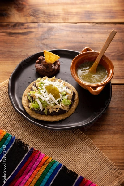 Fototapeta Sopes de Pollo. Traditional homemade Mexican appetizer prepared with fried corn dough covered with refried beans, green or red sauce, lettuce, cheese, onion and shredded chicken