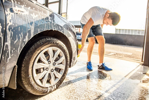 Fototapeta A man washes his car with foam at a self-service car wash