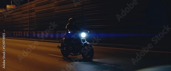 Fototapeta Biker riding his custom built cafe racer motorcycle through city at night. Shot with 2x anamorphic lens