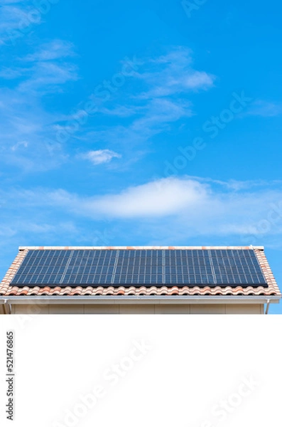 Fototapeta 白い文字スペースある太陽光パネルが設置された住宅の屋根と快晴の青空。