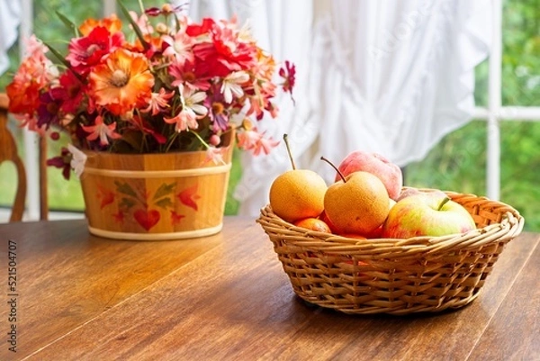 Fototapeta Autumn fruit basket on wooden table in front of window