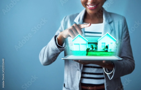 Fototapeta Corporate business woman holding a tablet with property cgi graphics while standing against a blue studio background alone. Happy, smiling and cheerful female designing a vr home with technology