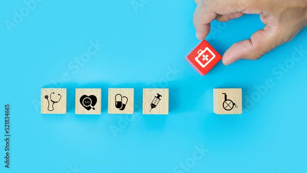 Fototapeta Hand choose medicine bag on cube wooden toy blocks stack with other health care and safety medical symbols concepts of healthy or sick prevent and illness treatment and insurance.