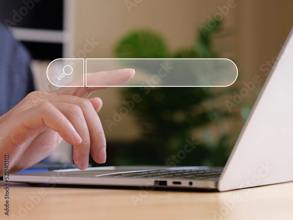 Fototapeta Man use finger touch virtual search bar with internet searching concept. Laptops is on wood table in front of a man.