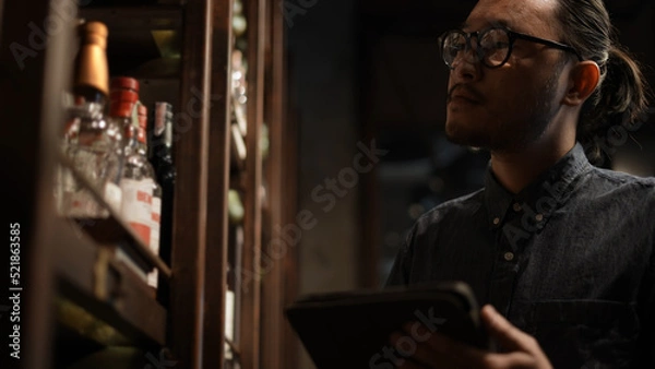 Fototapeta Night club concept of 4k Resolution. The bartender is checking the merchandise in the store. A group of specialized clubs that sell alcoholic beverages.