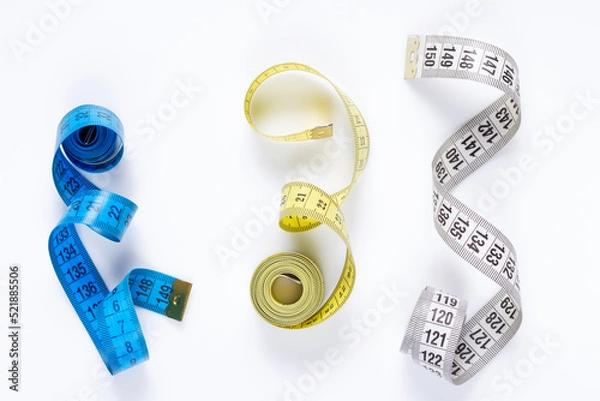 Fototapeta Tailor measuring tape at white background, top view. Tape measure on white