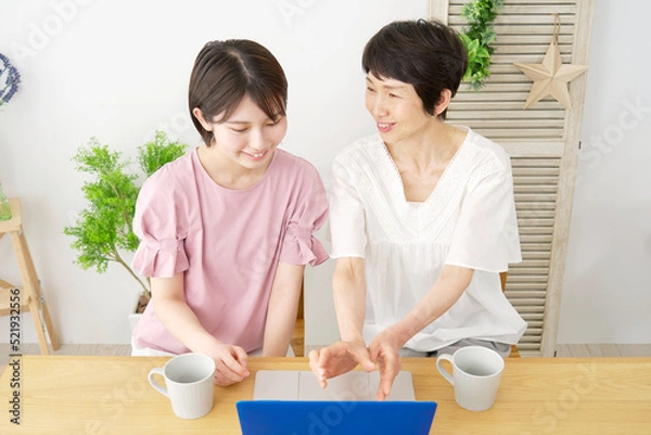 Fototapeta 自宅で母親とノートパソコンをを使う娘