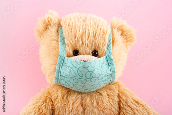 Obraz Teddy bear in protective medical mask on a pink background. Pediatrics concept.