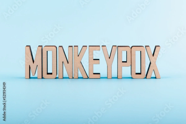 Obraz Wooden letters text MONKEYPOX on a blue background. Monkeypox virus concept.