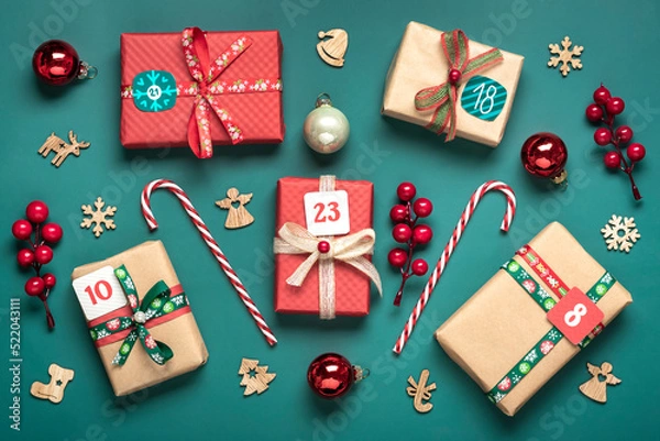 Fototapeta Xmas advent calendar concept Handmade wrapped red, green gift boxes decorated with ribbons, snowflakes and numbers, Christmas decorations and decor on green table Top view Flat lay Holiday card
