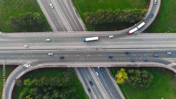 Obraz The drone flies over the track during traffic with many interchanges in different directions with a large number of cars that move one after another and change lanes to the desired exit from the track
