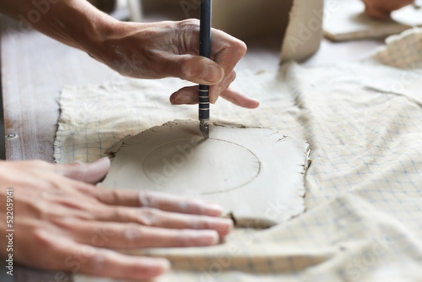 Fototapeta Female ceramist working in pottery studio. Ceramist's Hands Dirty Of Clay. Process of creating pottery. Master ceramist works in her studio