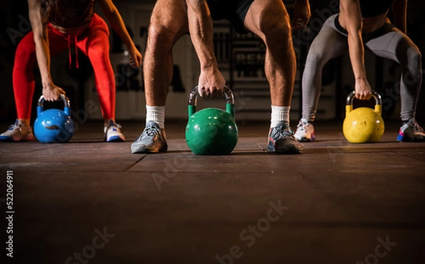 Fototapeta Group having functional fitness training with kettlebell in sport gym