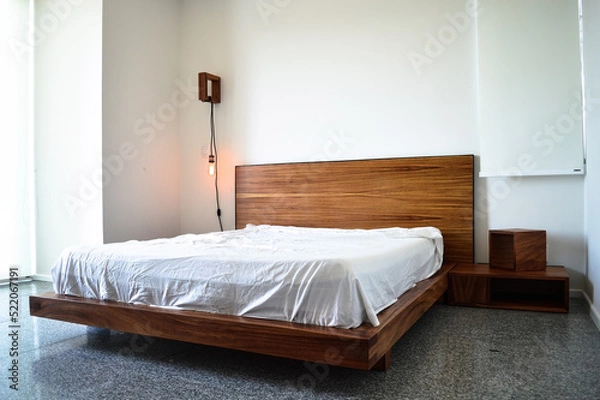 Fototapeta bed base, bedroom with mat on the floor, clay pot in the background, wooden credenza and mirror.