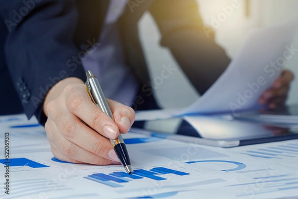 Fototapeta Close up business woman hand working analisys data with business graph information diagram on office desk as concept in morning light