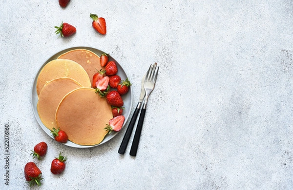 Fototapeta Delicate pancakes with strawberries on a concrete background. View from above.