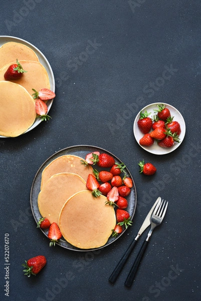 Fototapeta Delicate pancakes with strawberries on a concrete background. View from above.