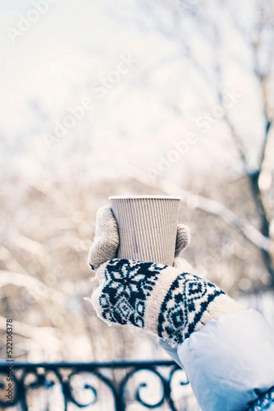 Fototapeta Hot drink in woman's hands wearing warm knitted gloves on cold winter snowy day.