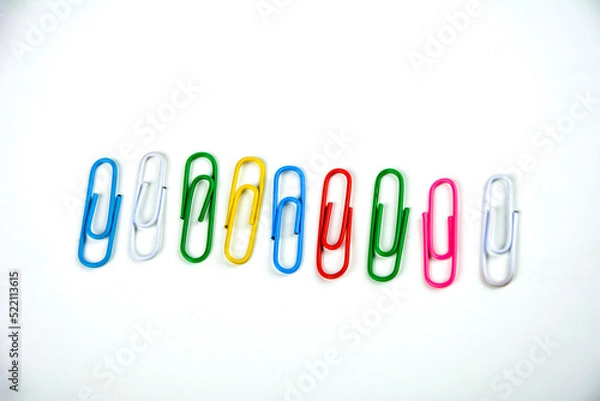 Fototapeta Colored paper clips on a white background.