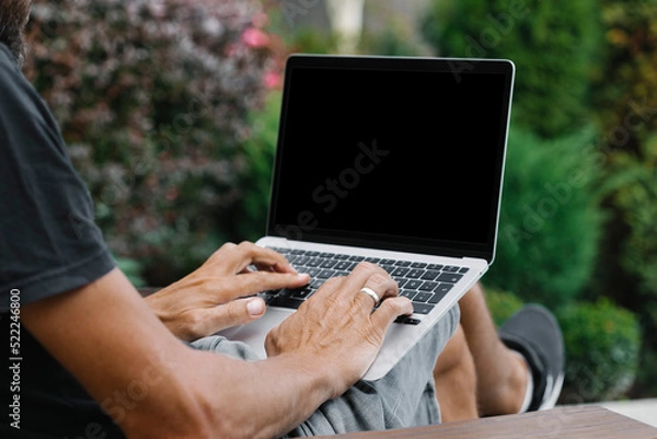 Fototapeta a man works in nature, sitting in a chair with a laptop