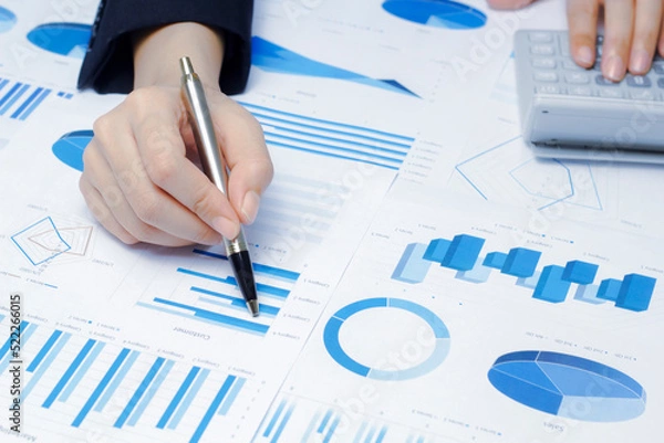Fototapeta Businessman holding a profitability statistics analysis pen from a graph document in hand  to plan profit.
