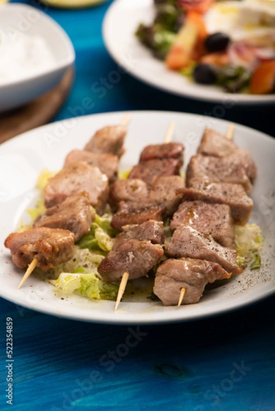 Fototapeta A grilled pork souvlaki served with greek salad