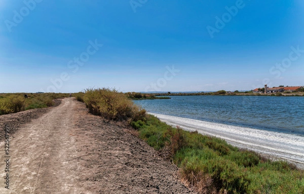 Fototapeta Tranquil view of the Samouco salt flats in Alcochete, Portugal, with still water reflecting the sky	