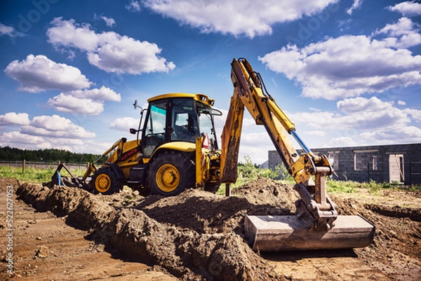 Fototapeta Excavator working at house construction site - digging foundations for modern house. Beginning of house building. Earth moving and foundation preparation.