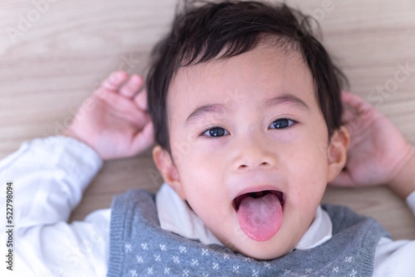 Fototapeta Close up Asian little cute boy happy sticking out tongue.