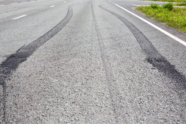 Fototapeta Burnouts on the asphalt made with a powerful muscle car. Skidmark or brake marks due to slippery road or accident. Dangerous driving or accident concept image.