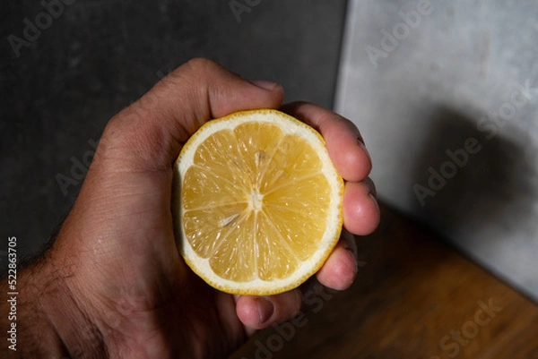 Fototapeta lemon in hand on wooden table