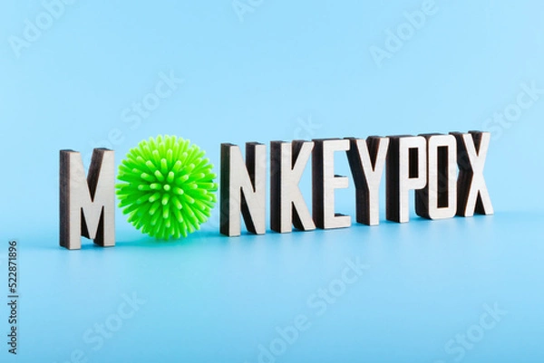 Fototapeta Wooden letters text MONKEYPOX on a blue background. Monkeypox virus concept.