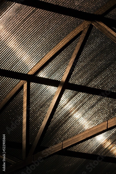 Fototapeta Canopy made of polycarbonate with drops of morning dew in sunny weather. Black metal construction. Bottom view.