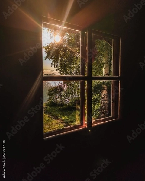 Fototapeta A beautiful summer view from finnish sauna window. Sunbeams shining through window.