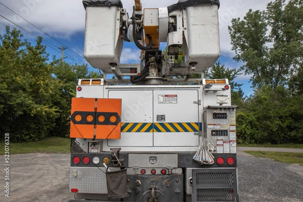 Fototapeta Rear view of an unmarked electrical utility hydro bucket  truck on a gravel lot, with view of baskets and boom, nobody