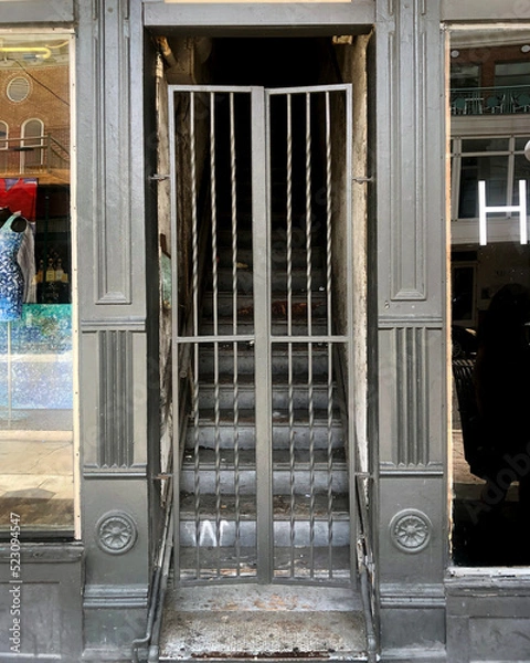Obraz Stairs to an apartment behind a grey painted iron gate that leads to a busy city street 