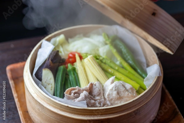 Obraz 和食レストランで提供される、ヤングコーンやアスパラガスなど色鮮やかな夏野菜と豚肉のヘルシーなせいろ蒸し。湯気が立ち昇るシズル感のあるアップ写真