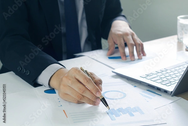 Fototapeta Business man analyzing chart and graph showing changes on the market.On the table in the office, the concept of calculating investment results.