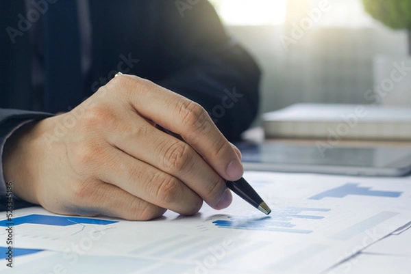 Fototapeta Close up of a Business man hand analyzing chart and graph showing changes on the market.