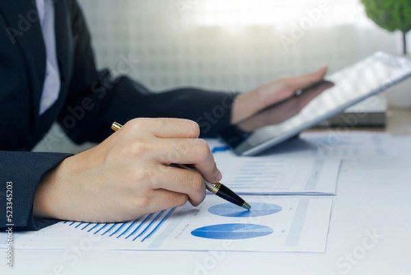 Fototapeta Close up of a businesswoman hand using a tablet to verify of business principles. Accounting statistics concept at the office.