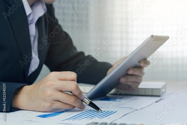 Fototapeta Close up of a businesswoman hand using a tablet to verify of business principles. Accounting statistics concept at the office.