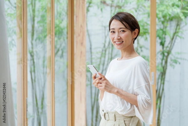 Fototapeta リビングでスマートフォンを使う若い女性