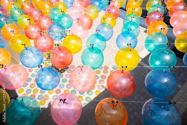 Fototapeta 中空に飾られたたくさんのカラフルなバルーンと地面に映る影